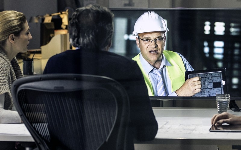 Architect in hard hat on site video calling business team